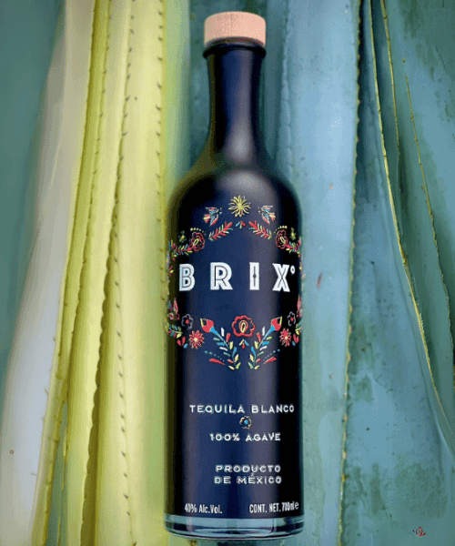 Una botella de tequila Brix sobre hojas de agave