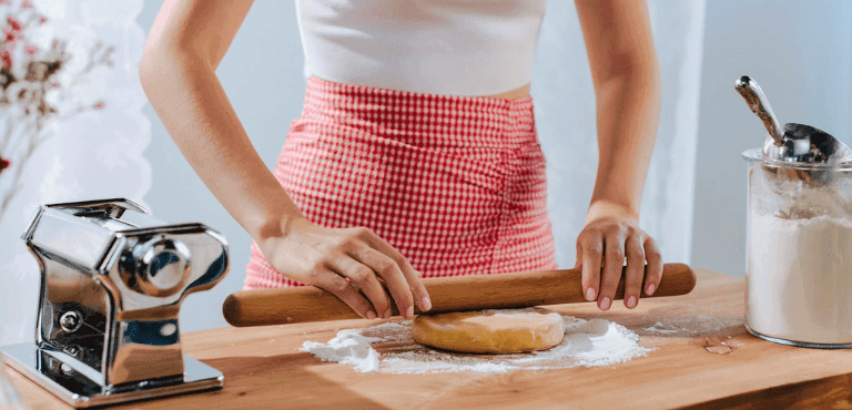 mujer en la cocina con un rodillo aplasta una masa de hojaldre