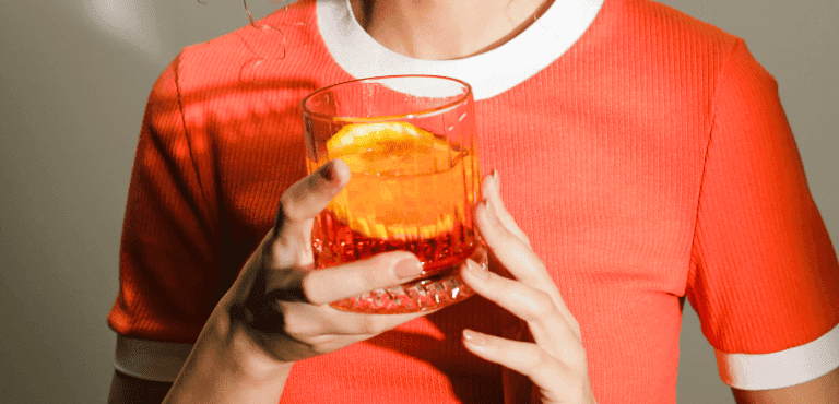 mujer sostiene un vaso de negroni