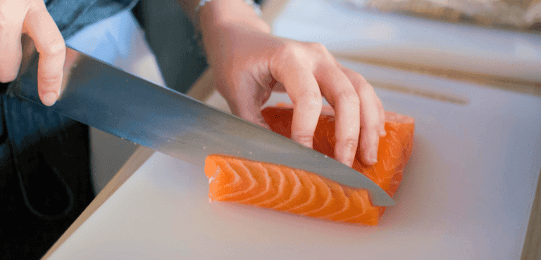 una manos cortan un salmón con un cuchillo