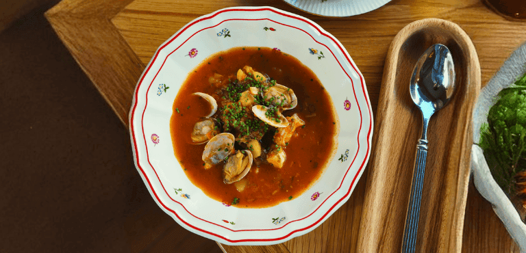 un plato de sopa de mariscos casera con una cuchara de metal