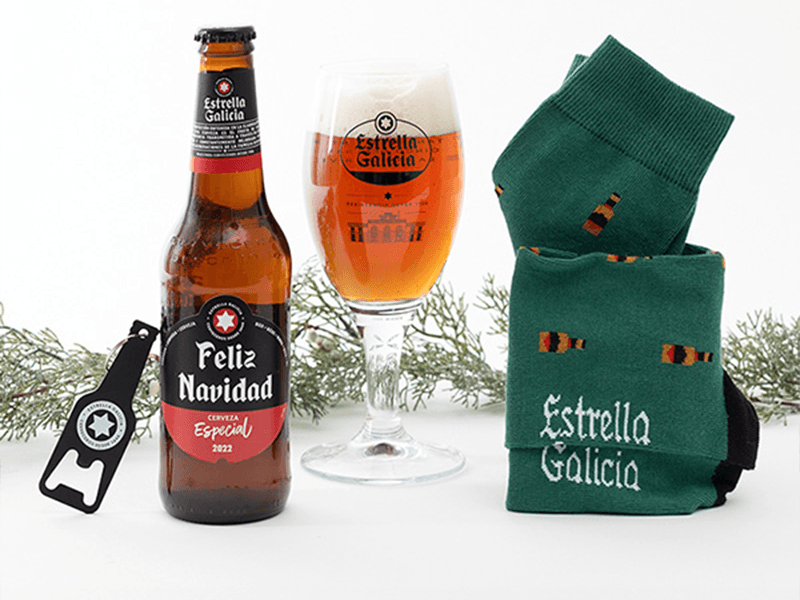 pack amigo invible, con una botella de estrella galicia personalizada con el mensaje feliz navidad una copa con cerveza y unos calcetines verdes con botellas