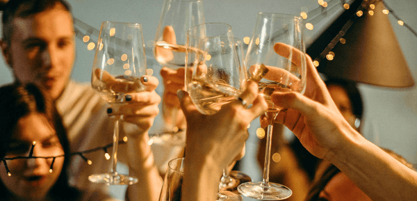Un grupo de personas realizan un brindis de Fin de Año perfecto siguiendo los consejos de este artículo que recomienda las mejores bebidas para brindar en esta temporada navideña