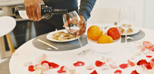 Un hombre sirve una copa de vino tinto para celebrar el amor con una cena inolvidable con menús para San Valentín para parejas que disfrutan comiendo y bebiendo