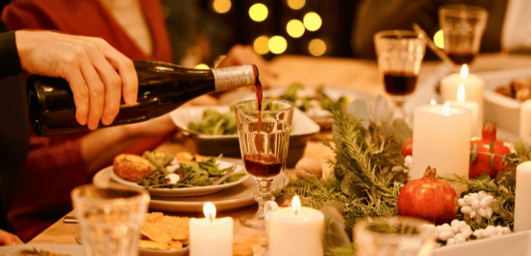 Persona sirve una copa de vino que llevó a la cena de Navidad para compartir con los seres queridos y quedar bien ante los anfitriones