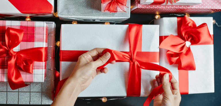 Persona envuelve varias cajas de regalos ideales para dar el Día de la Madre con opciones especiales para esas madres que dicen que no quieren nada