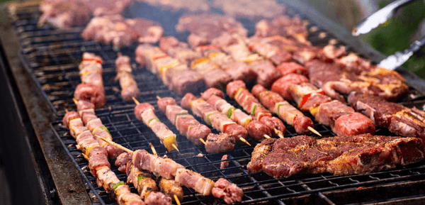 Varios cortes y tipos de carnes en una barbacoa humeante y deliciosa.