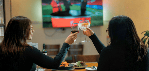 Dos amigas disfrutan de los mejores partidos de fútbol europeo bebiendo vino y comiendo cenas gourmet express perfectas para ver partidos