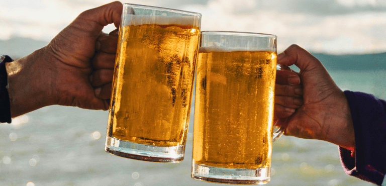 dos personas brindan con dos jarras de cervezas sin alcohol