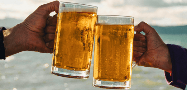 dos personas brindan con dos jarras de cervezas sin alcohol