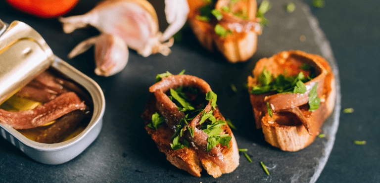 Un plato con tapas y conservas de pescado para un picoteo delicioso en cualquier ocasión.