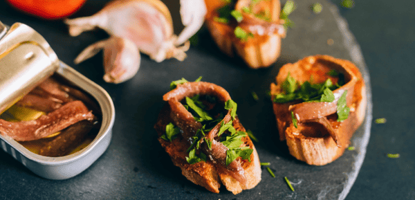Un plato con tapas y conservas de pescado para un picoteo delicioso en cualquier ocasión.