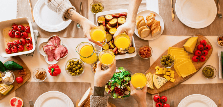 Unas personas brindan en una mesa en un desayuno o brunch gourmet que se puede preparar en el hogar con recetas sencillas y los mejores productos que se pueden comprar online para disfrutar sin complicaciones