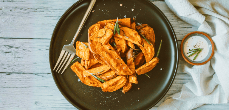un plato con chips de boniato con un pequeño bowl de salsa sobre el cual para mojar los chips crujientes de boniato que añaden un toque dulce y un ligero picante que despierta los sentidos