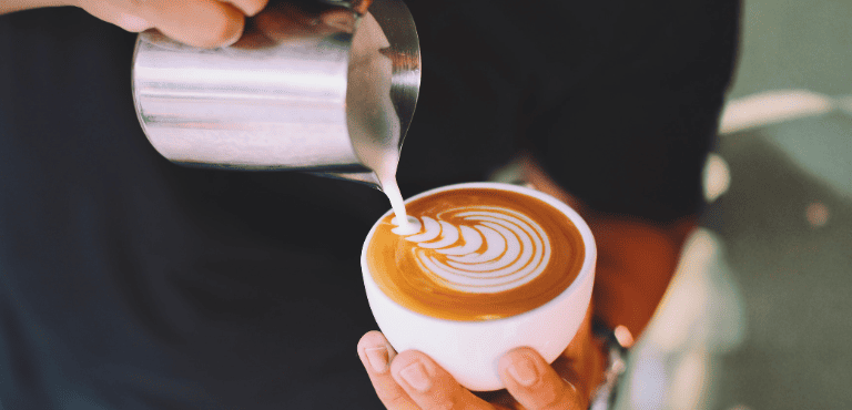 Una persona prepara una taza de café con leche hecho con café de especialidad para un sabor premium.