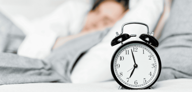 Una alarma y una persona durmiendo, que marca el inicio de la rutina en la mañana.
