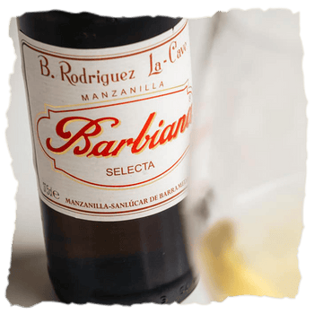 Botella y copa de Manzanilla Barbiana, una manzanilla pasada 100% Palomino de crianza biológica durante cinco años, sabrosa, marina y representante de la más pura tradición de Sanlúcar de Barrameda.