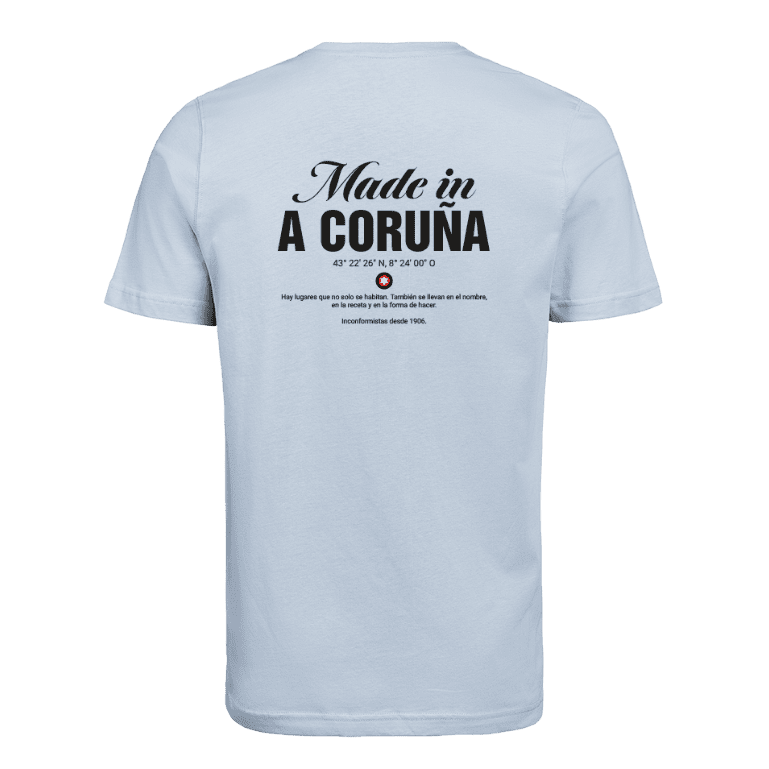 Camiseta Estrella Galicia de tela de algodón azul claro de camiseta con serigrafía negra detallada del texto "Hecho en A Coruña", coordenadas, logotipo de estrella y una cita en español.