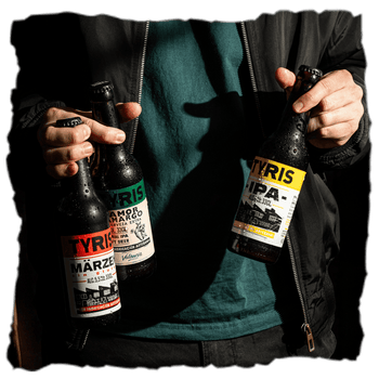 un hombre sostiene tres botellas de 33 cl de cervezas Tyris, una Marzen, una Amor Amargo y una IPA, hechas con fabricación artesanal en Valencia