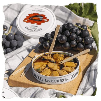 una lata de mejillones de Conservas La Curiosa y uvas en un picnic, estas conservas resultan perfectas como aperitivo y combinan con muchos otros alimentos