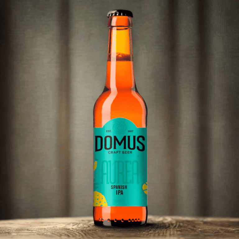 una botella de Domus Aurea IPA, refrescante dorada con notas tropicales y cítricos, amargor suave, premiada y perfecta para compartir