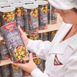 Una trabajadora de Sarasa sostiene una lata grande de Aceitunas Sarasa Receta del Cortijo, perfectas para un picoteo o para preparar diversas recetas.