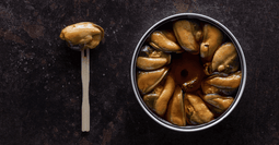 una lata abierta de Mejillones en escabeche picante de La Curiosa, una conserva gourmet de la Ría de Arousa, fritos y empacados a mano con escabeche aromático y guindillas que intensifican su sabor picante