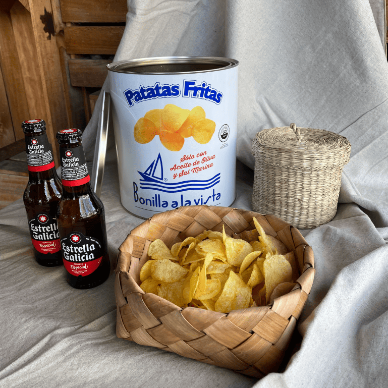 un pack con botellas de Estrella Galicia Especial de 25 cl, cada una con su característico sabor y aroma que se combina perfectamente con la textura crujiente y el sabor salado de una lata de patatas Bonilla a la vista de 500 g