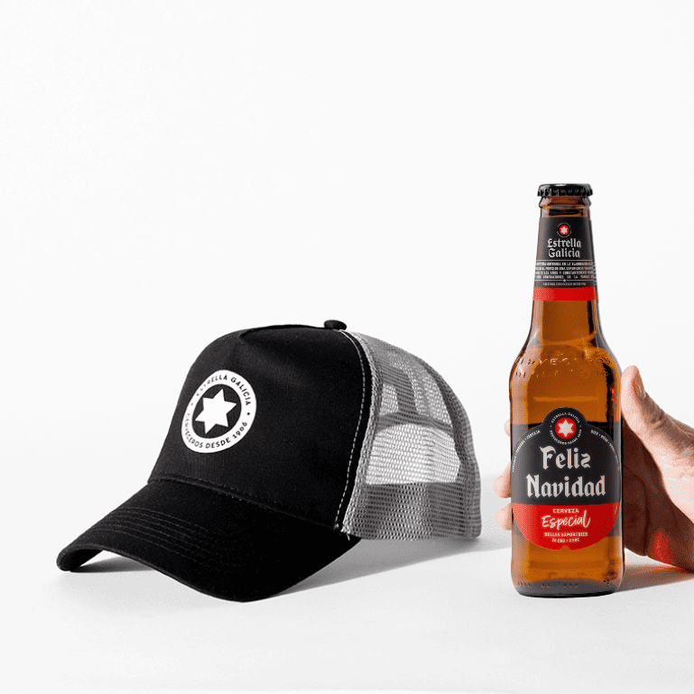 Un Pack Feliz Navidad con la gorra de Estrella Galicia que combina estilo, comodidad con pasión cervecera, una mano sostiene la botella de cerveza edición especial de Navidad que es un regalo perfecto para sorprender a amigos y familiares