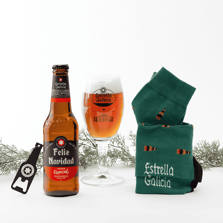 Un pack Amigo Invisible de Estrella Galicia, que incluye un estuche de cerveza Estrella Galicia edición Feliz Navidad, un par de calcetines verdes y llavero negro, siendo un regalo perfecto para compartir durante estas fechas y sorprender a esa persona especial