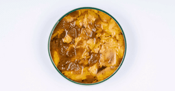 una lata abierta de Ventresca de atún al curry de La Curiosa, una jugosa ventresca con cebolla pochada, pimiento Espelette y suave curry verde, ideal sola o acompañada