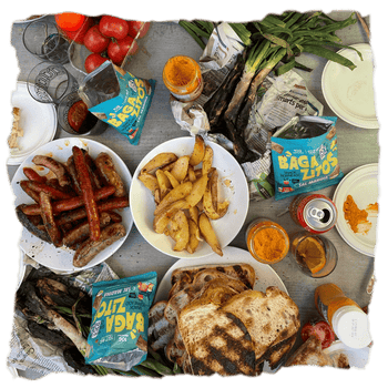 Una mesa con alimentos y bolsas de Bagazitos para descubrir cómo el upcycling puede convertir la cebada en el aperitivo más sabroso del mercado que combina con muchas opciones.