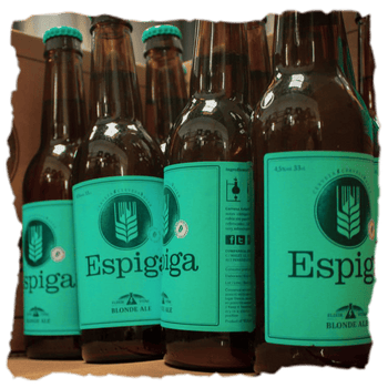 Botellas de Espiga Blonde Ale una cerveza rubia artesanal, refrescante y ligera, que destaca por sus notas cítricas y frutales, un cuerpo suave y un amargor sutil muy equilibrado.