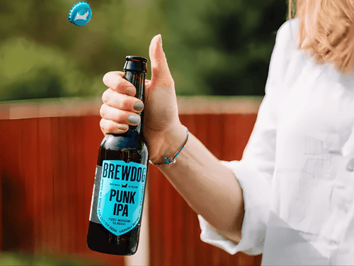 Una mujer destapa una botella de cerveza escocesa Brewdog, que son intensas y maltosas, ideales para cualquier ocasión por su amplia variedad de estilos