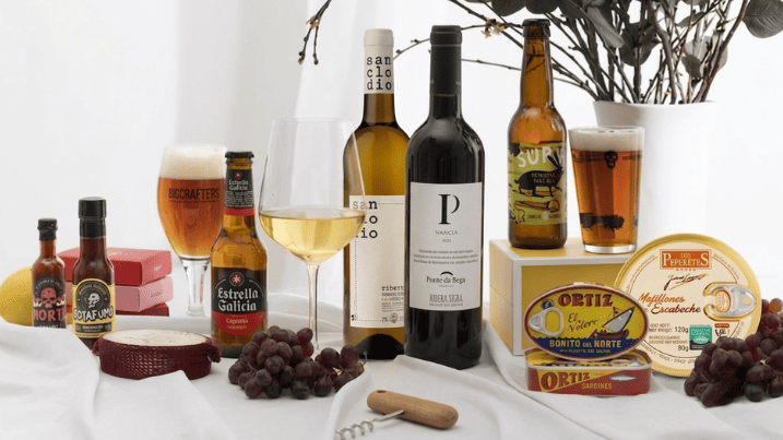 Un bodegón de productos gourmet sobre un mantel blanco con cervezas, vinos, conservas, salsas y más para disfrutar de un maridaje completo.