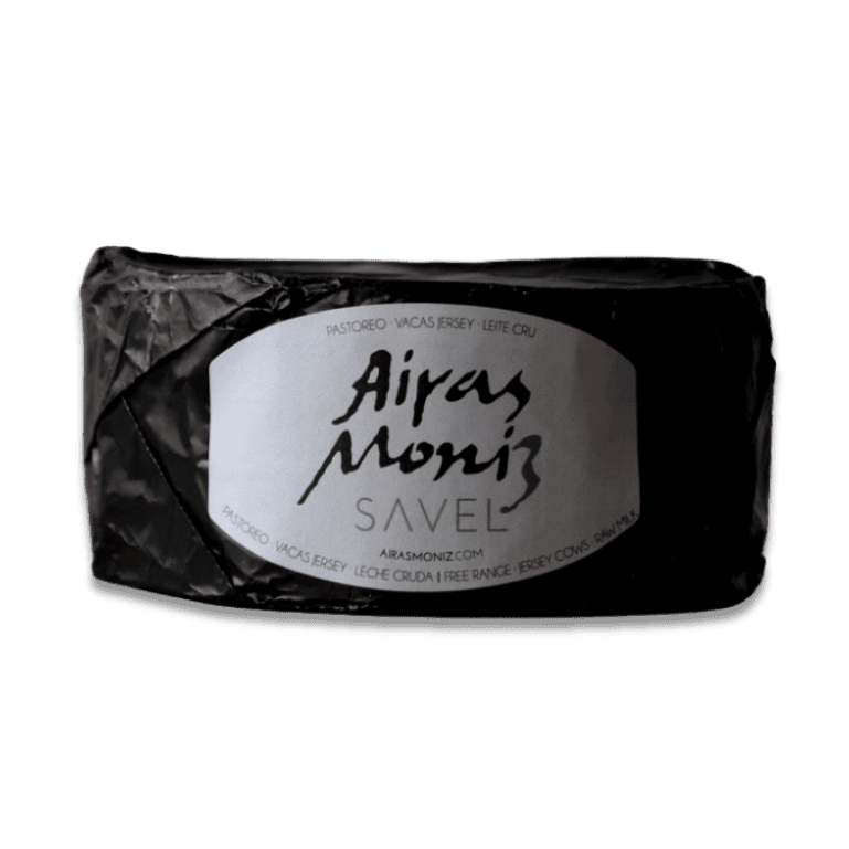 pieza de  queso Savel de Airas Moniz, un queso azul único y rebelde, elaborado con leche cruda de vaca Jersey, que sorprende por la intensidad de sus vetas azul-verdosas y una textura tan untuosa que se funde en la boca como mantequilla.
